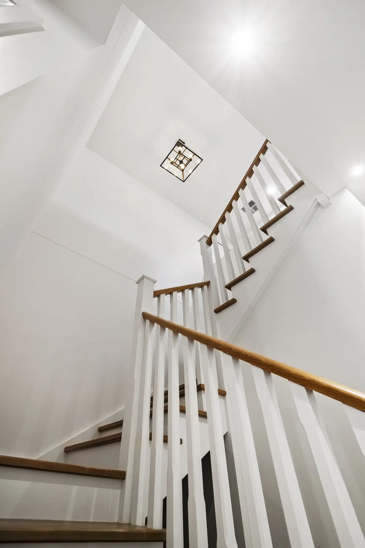 White stairwell with timber handrails and a window above the landing