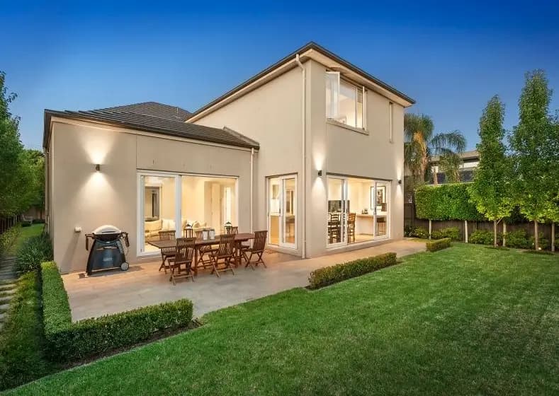 Two-storey home with large windows opening onto an outdoor dining patio