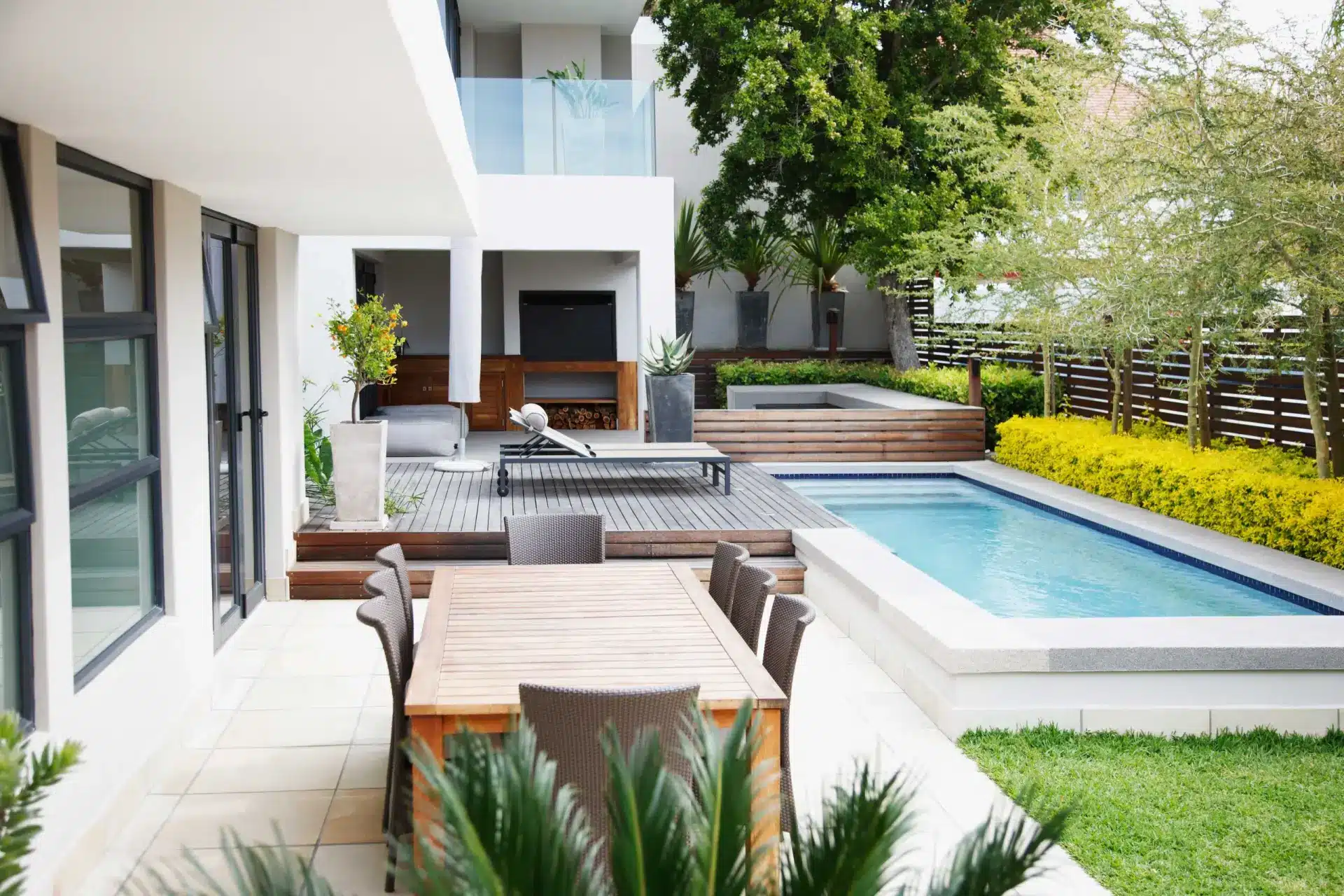 Outdoor dining patio beside a swimming pool and a modern house