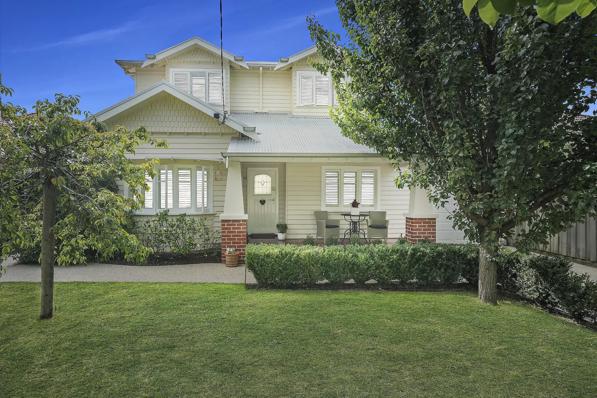 Two-storey weatherboard home overlooking a lawn and garden
